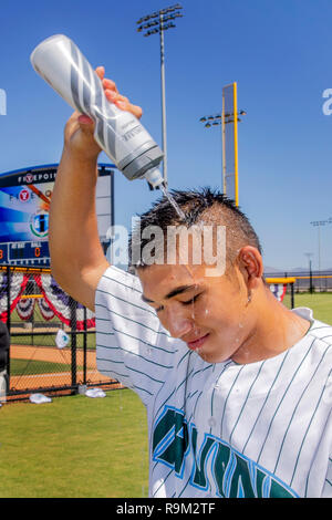 In un caldo pomeriggio estivo presso un Irvine, CA, softball stadium, un lettore in uniforme non si raffredda con uno spruzzo di acqua. Foto Stock