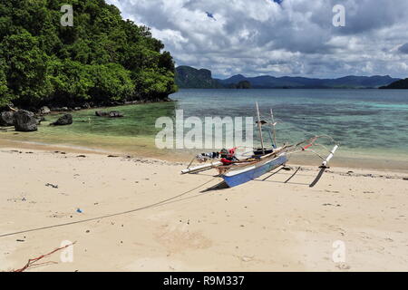 E-reparti vista dal punto Cudugnon Cave Beach oltre spiaggiata vecchio bangka filippino-tour in barca per la island hopping attraverso Bacuit bay di Palawan continentale e la Foto Stock