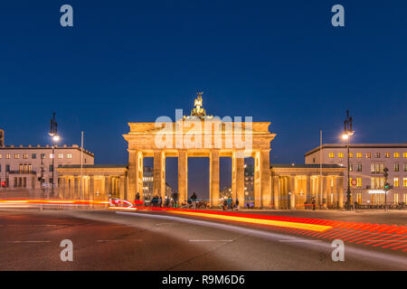 La Porta di Brandeburgo di Berlino di notte con vista posteriore. Lanterne di illuminare la strada. Luce delle luci di posizione posteriori di veicoli in transito durante una lunga esposizione Foto Stock