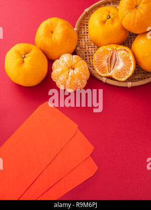 Bella e deliziosa tangerine isolato su sfondo rosso con il nuovo anno cinese decorazioni, close up, spazio di copia Foto Stock