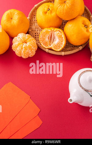 Bella e deliziosa tangerine isolato su sfondo rosso con il nuovo anno cinese decorazioni, close up, spazio di copia Foto Stock
