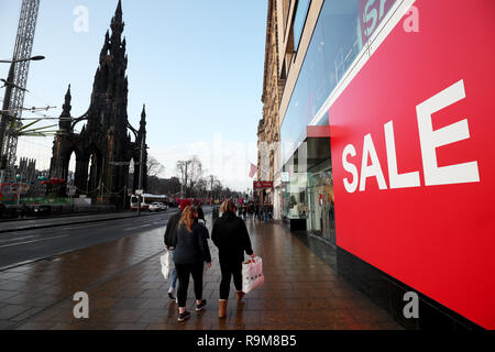 Agli acquirenti di passare un segno di vendita nella vetrina di un negozio su Princes Street, Edinburgh, durante il Boxing Day vendite. Foto Stock
