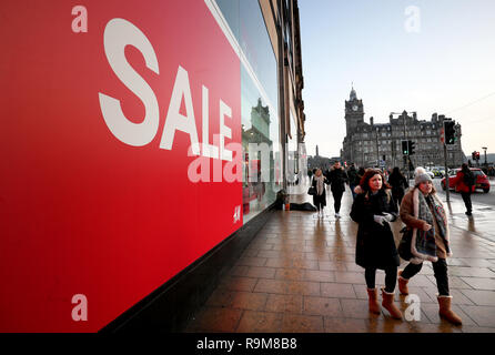 Agli acquirenti di passare un segno di vendita nella finestra di H&M su Princes Street, Edinburgh, durante il Boxing Day vendite. Foto Stock