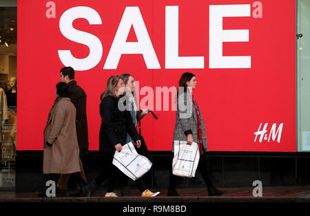 Gli acquirenti passano un cartello di vendita nella finestra di H&M su Princes Street, Edimburgo, durante le vendite del giorno di Santo Stefano. Foto Stock