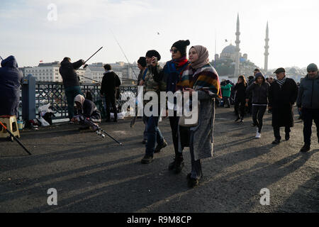 Istanbul, Turchia - 22 Dicembre 2018 : due giovani donne turche stanno camminando sul Ponte Galata. Uno di essi è tenuto selfie.altre persone sono la pesca Foto Stock