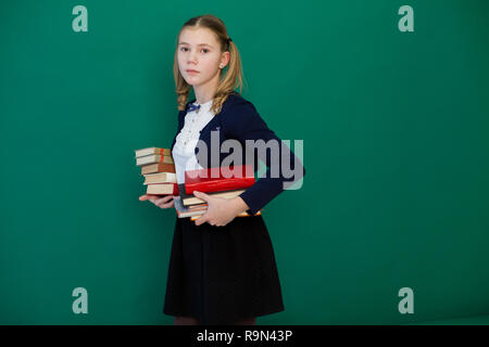 Schoolgirl ragazza durante una lezione alla lavagna con libri Foto Stock