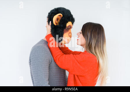 Divertente coppia giovane, ragazzo che indossa la maschera di scimmia, pazzo idiota e rapporto di amore Foto Stock