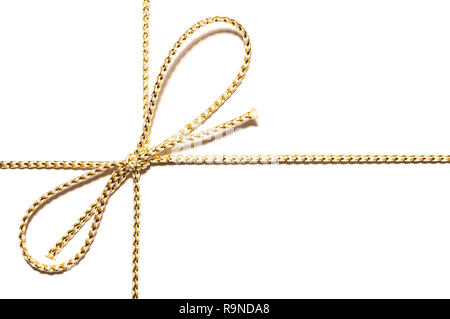 Golden satinata con corda annodata bow dono di avvolgimento a nastro per il regalo di Natale con intricati dettagli shine isolato ritagliata su semplice carta bianca comune e nuova backgrou Foto Stock