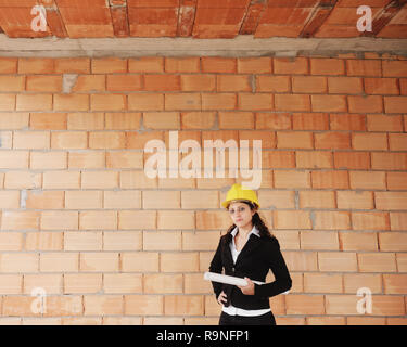 La donna nel nuovo progetto di alloggiamento. Ritratto di felice architetto femmina tenendo i progetti di un edificio. Donna adulta cercando e sorridente a telecamera con spazio di copia su Foto Stock