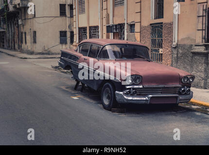 Vecchia auto arrugginito sollevato per le strade di La Habana Cuba. Si tratta di un american old timer con le ruote posteriori mancanti. Il quadro fornisce un vintage styling Foto Stock