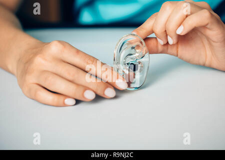 Close-up di un medici mano azienda moderna Hearing Aid. apparecchi acustici-trattamento sordità Foto Stock