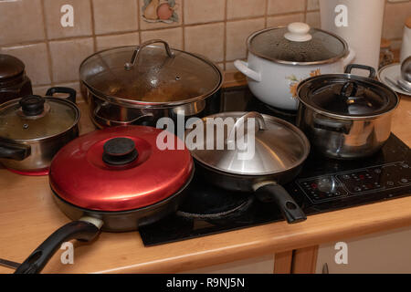 Pentole con piatti cucinati su una cucina elettrica. Un pasticcio sul tavolo della cucina. Sfondo chiaro. Foto Stock