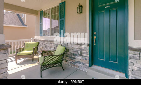 Verde porta anteriore con due poltrone in veranda Foto Stock