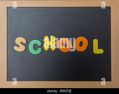 Il concetto di scuola. Lavagna nera con cornice in legno, word, scuola di testo in lettere colorate Foto Stock