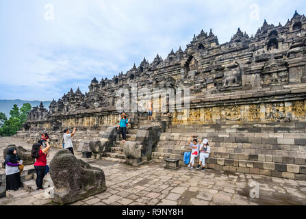 Visitatori presso la salita al mandala passo piramide del IX secolo tempio Buddhista di Borobudur e Java centrale, Indonesia Foto Stock