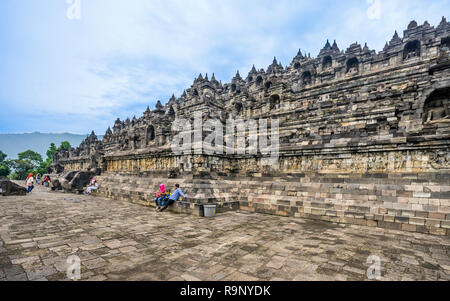 I visitatori in appoggio alla base terrazza del mandala passo piramide del IX secolo tempio Buddhista di Borobudur e Java centrale, Indonesia Foto Stock