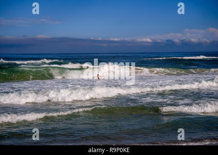 Bella giornata sulla spiaggia a Florianópolis isola. Irriconoscibile l uomo è diving in una grande onda al mare. Spiaggia di Campeche, Santa Catarina Island, Brasile. Foto Stock