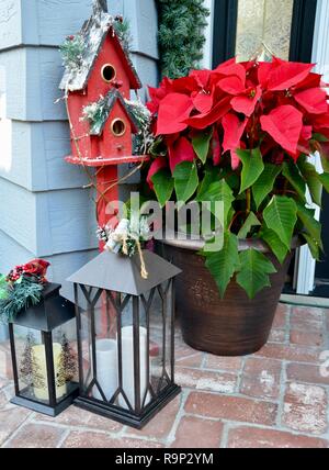 Festive vacanze inverno decorazioni accolgono gli ospiti con i tradizionali a tema natalizio elementi come i poinsettias, un rosso birdhouse e lanterne. Foto Stock