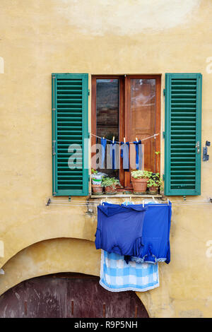 Finestra tradizionale con persiane di legno della vecchia casa. Servizio lavanderia appesi da Windows a Siena. Italia Foto Stock