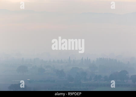 Moody vista della valle Umbra (Italia) nel mezzo della nebbia d'autunno Foto Stock