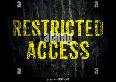 Accesso ristretto Avvertenza pericolo sign in giallo lettere dipinte su dark grungy calcestruzzo di cemento parete. Concetto di segno per non entrare nella zona, attenzione Foto Stock