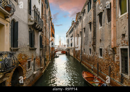 I turisti attraversare un ponte su un canale residenziale fuori dal percorso battuto con una cattedrale del campanile in vista sul Canal Grande a Venezia, Italia Foto Stock