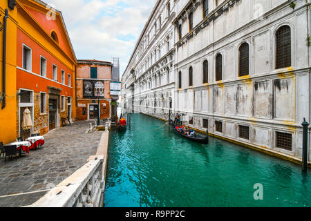 Un gondoliere veneziano con una famiglia di turisti nella sua gondola, manzi passato una piccola piazza vicino al Ponte dei Sospiri a Venezia, Italia Foto Stock