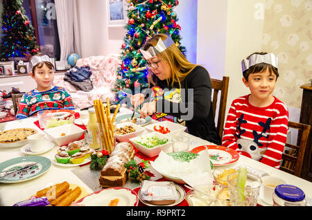 Una famiglia sedersi a un tavolo da pranzo stabiliti con insalata per un tè di Natale, Foto Stock