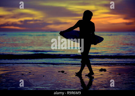 Silhouette di un surfista voce nell'acqua durante il sunrise. Surfer al tramonto del tempo. Tramonto sulla spiaggia con surfer guardando le onde. Foto Stock