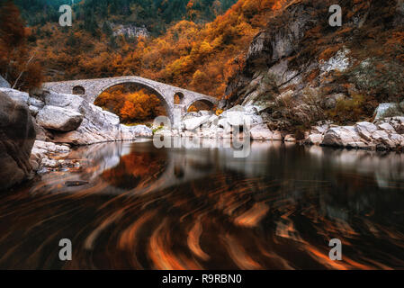 Ponte del Diavolo, Bulgaria. Antico ponte di pietra sul fiume Arda, tempo d'autunno con foglie in acqua. Sui monti Rodopi Foto Stock