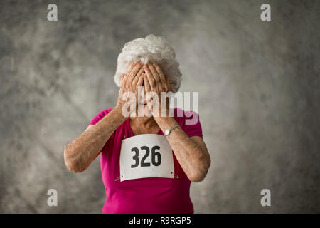 Giocoso senior donna che copre il volto con le mani. Foto Stock