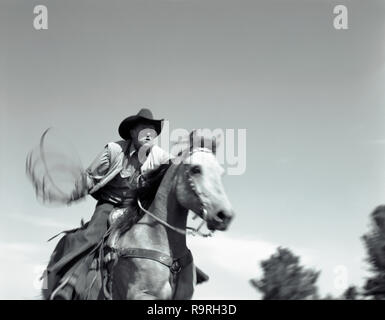 Coppia cowboy a cavallo ed oscillante un laccio all'esterno. Foto Stock