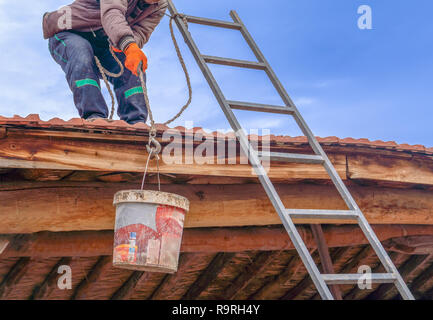 Lavoratore tira calcestruzzo bagnato via benna per il tetto in zona rurale Foto Stock