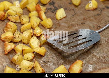 Patate al forno cosparso di spezie. Le verdure tagliate a cubetti preparato per servire in tavola. Luogo - cucina domestica. Foto Stock