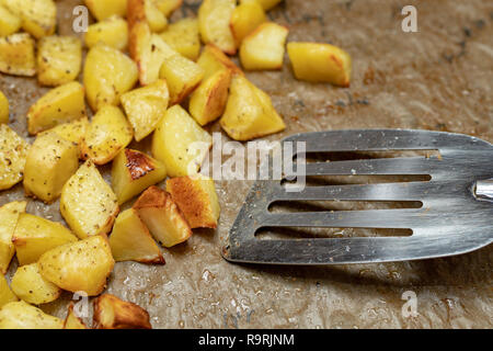 Patate al forno cosparso di spezie. Le verdure tagliate a cubetti preparato per servire in tavola. Luogo - cucina domestica. Foto Stock