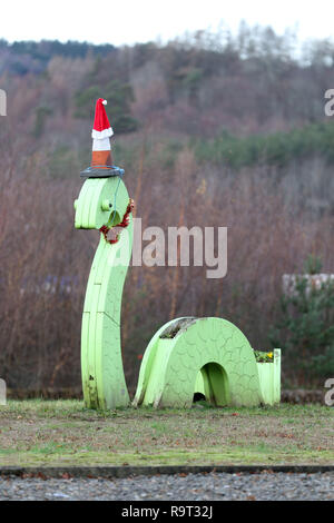 Inverness, Scotland, Regno Unito. Il 29 dicembre 2018. Burloni hanno vestito un punto di riferimento del mostro di Loch Ness in un cono stradale, Santa hat e un tinsel collana. Il legno Nessie è in corrispondenza di una rotatoria sulla strada per il Lago di Loch Ness da Inverness, vicino al negozio Tesco sulla Dores road. L'aggiunta di traffico cono al Nessie landmark è simile al normale aggiunta di un cono stradale per il Duca di Wellington statua in Glasgow. Credito Foto: Andrew Smith/Alamy Live News Foto Stock