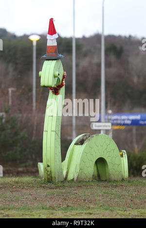 Inverness, Scotland, Regno Unito. Il 29 dicembre 2018. Burloni hanno vestito un punto di riferimento del mostro di Loch Ness in un cono stradale, Santa hat e un tinsel collana. Il legno Nessie è in corrispondenza di una rotatoria sulla strada per il Lago di Loch Ness da Inverness, vicino al negozio Tesco sulla Dores road. L'aggiunta di traffico cono al Nessie landmark è simile al normale aggiunta di un cono stradale per il Duca di Wellington statua in Glasgow. Credito Foto: Andrew Smith/Alamy Live News Foto Stock