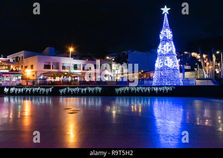 Vista notturna della città vecchia e di albero di Natale con i turisti in Puerto del Carmen Isole Canarie Spagna. Foto Stock