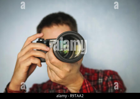 Ritratto di un fotografo di eleganti vestiti casual in camicia in piedi con la fotocamera su sfondo blu. copyspace, copia, spazio Foto Stock