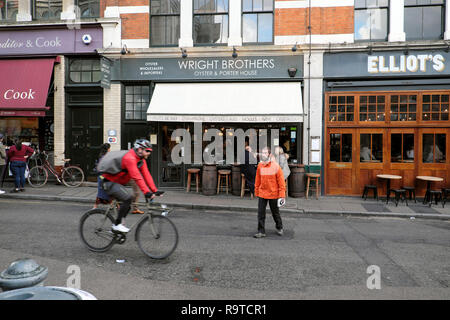 Ciclista maschio in sella alla sua moto che indossa un casco ciclismo passato fratelli Wright Oyster & Porter House su Park Street a Londra SE1 Inghilterra DEWIT KATHY Foto Stock