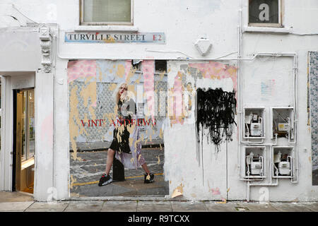 Poster adornato con il modello di Vinti Andrews defatto e lacerato con graffiti sul muro a Turville Street Shoreditch East London E2 KATHY DEWITT Foto Stock