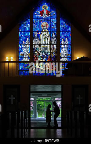 Middletown, CT, Stati Uniti d'America. Maggio 2009. Silhouette di madre preparare bambino all ingresso della chiesa per la sua prima comunione cattolica. Foto Stock