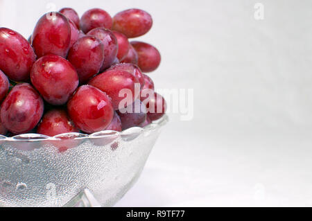 Grappolo di rosso senza semi uva (Vitis vinifera) in una ciotola di vetro Offset Foto Stock