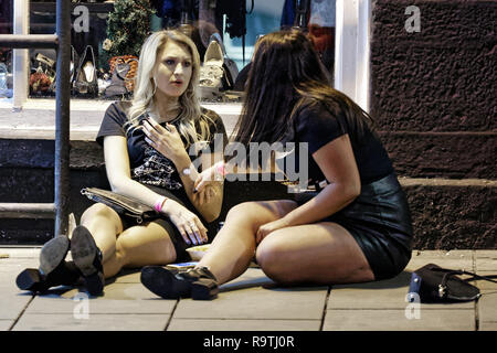 Nella foto: due donne siedono sul marciapiede. Venerdì 14 Dicembre 2018 Re: festaioli nel vento Street, Swansea, Wales, Regno Unito. Foto Stock