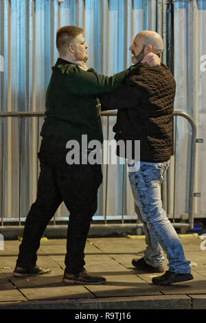 Nella foto: due uomini spingono reciprocamente. Venerdì 14 Dicembre 2018 Re: festaioli nel vento Street, Swansea, Wales, Regno Unito. Foto Stock