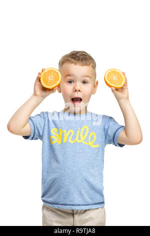 A piena lunghezza Ritratto di carino capretto piccolo ragazzo in abiti eleganti con orange in piedi contro studio bianco parete. Kids Fashion Concept Foto Stock