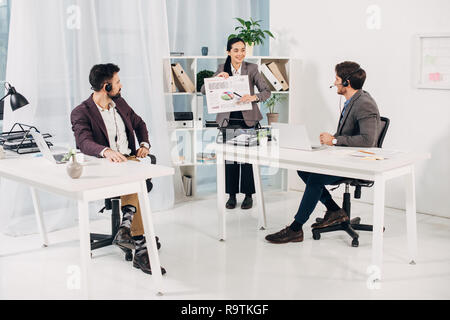 Donna manager mostra i grafici e i diagrammi a maschio i colleghi in ufficio Foto Stock