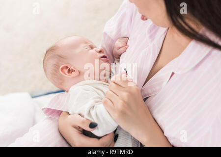 Vista parziale di madre calmate piccolo bimbo che piange sulle mani Foto Stock