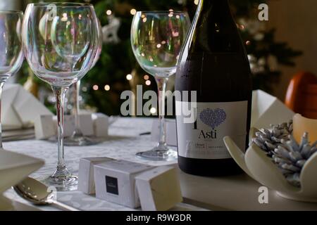 Bicchieri di vino e una bottiglia di Asti con le luci di Natale in background Foto Stock