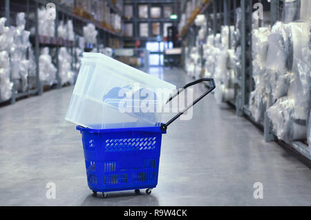 Plastica carrello blu con la merce nel magazzino del negozio. Grande magazzino di merci. Foto Stock